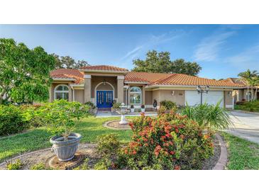 Charming single-story home with a well-manicured lawn, mature trees, and a red tile roof at 387 Eden Dr Dr, Englewood, FL 34223
