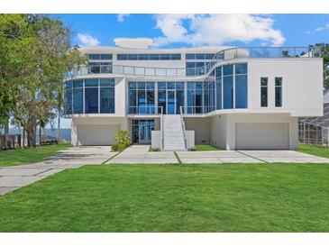Modern waterfront home with sleek white exterior, glass windows, and an expansive driveway with manicured lawn at 4035 Bay Shore Rd, Sarasota, FL 34234