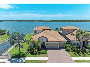 Beautiful lakefront house with stunning water views, lush landscaping, and brick paved driveway at 501 Maraviya Blvd, Nokomis, FL 34275