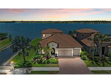 Stunning waterfront home featuring lush landscaping, a paver driveway, and a tile roof at 501 Maraviya Blvd, Nokomis, FL 34275