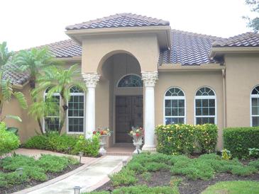 Inviting home exterior with arched entry, decorative columns, and meticulously maintained landscaping at 3230 Charles Macdonald Dr, Sarasota, FL 34240
