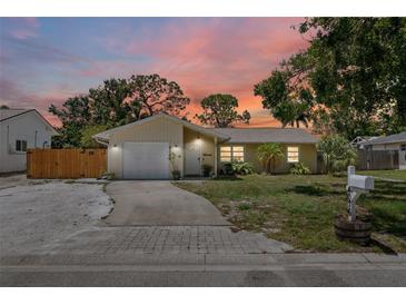 Charming single-story home with an attached garage and well-maintained front lawn at sunset at 4076 Vana Dr, Sarasota, FL 34241