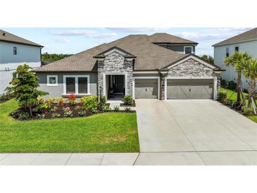 Charming single-Gathering home featuring a stone facade, well-manicured lawn, and a two-car garage at 4430 Pond Brook Ct, Bradenton, FL 34211