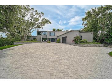 Expansive brick driveway leads to a contemporary stucco home with mature landscaping at 512 Treasure Boat Way, Sarasota, FL 34242