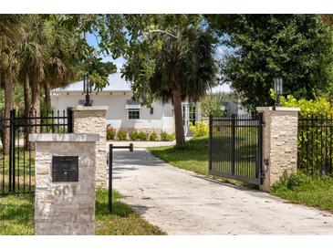 Charming home featuring a stone gate entrance with a long private driveway and lush landscaping at 601 Suffolk Cir, Nokomis, FL 34275