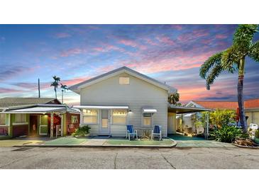Charming home exterior with a light color, palm trees, and a cozy seating area at 14 Braden Castle Dr, Bradenton, FL 34208