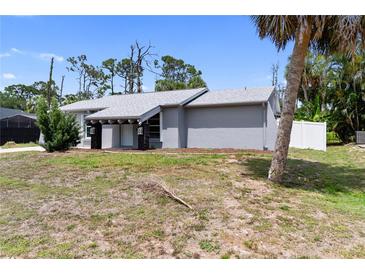 Charming single-story home featuring a modern gray exterior, crisp white trim, and well-manicured landscaping at 16834 Toledo Blade Blvd, Port Charlotte, FL 33954