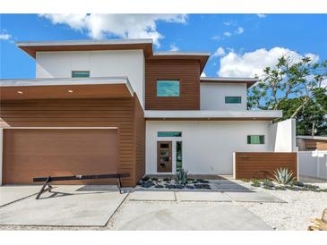 Modern two-story home featuring a sleek design with wood-tone accents and a landscaped front yard with stone walkway at 2314 Floyd St, Sarasota, FL 34239