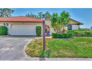 Front exterior of the home boasts a red tile roof, attached garage, and lush landscaping for enhanced curb appeal at 5651 Golf Pointe Dr # 5651, Sarasota, FL 34243