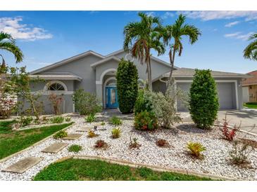 Charming single-story home with lush tropical landscaping, stone pathway, and a vibrant turquoise front door at 6113 55Th E Ter, Bradenton, FL 34203