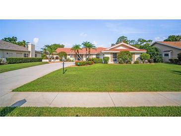 Well-manicured lawn and landscaping accent this beautiful single-story home with a red-tile roof at 7804 Broadmoor Pines Blvd, Sarasota, FL 34243