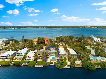 Waterfront home featuring private pool, lush landscaping, and spectacular bay views on a sunny day at 8234 Midnight Pass Rd, Sarasota, FL 34242