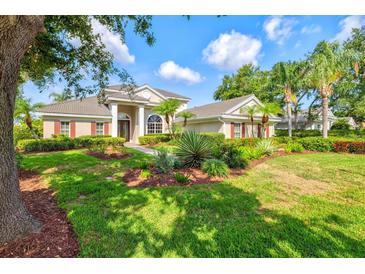 Beautiful home featuring a well-manicured lawn, lush landscaping, and mature trees at 8930 Bloomfield Blvd, Sarasota, FL 34238