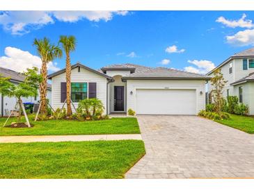 Charming one-story home with a two-car garage, well-manicured lawn, and beautiful palm trees at 10868 Sun Drop St, Venice, FL 34293