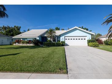 Charming light-blue home with a well-manicured lawn, landscaping, and a two-car garage at 1279 Vermeer Dr, Nokomis, FL 34275