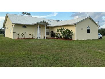 Charming single-story home with a metal roof, manicured lawn, and lush landscaping at 4353 Hidden River Rd, Sarasota, FL 34240