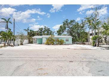 Charming single-story beach home featuring a metal roof and tropical landscaping and a large, sandy yard at 5026 Calle Minorga, Sarasota, FL 34242