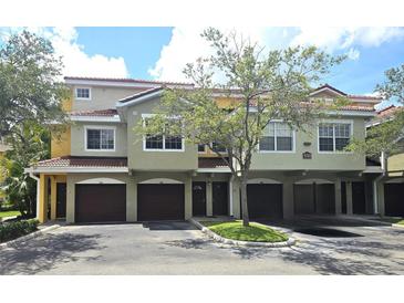 Charming townhome featuring a red tile roof, private garages, and beautiful landscaping at 5711 Bentgrass Dr # 19-203, Sarasota, FL 34235