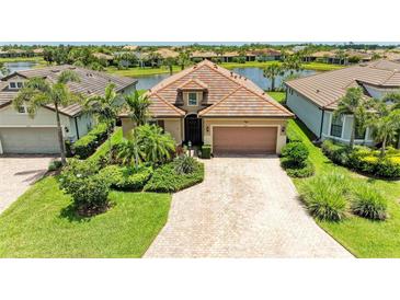 Charming home with tile roof, brick driveway, and lush landscaping near a tranquil lake at 6756 Chester Trl, Lakewood Ranch, FL 34202