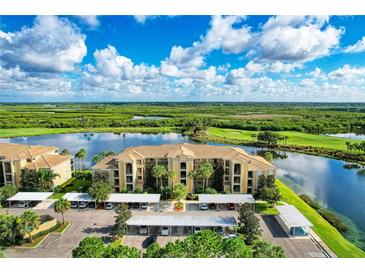 Stunning aerial view of condo complex overlooking a serene lake and lush golf course under a partly cloudy sky at 7911 Grand Estuary Trl # 102, Bradenton, FL 34212