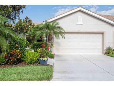 Charming home with a lush, landscaped front yard and a two-car garage with light stucco at 8224 Simpson Falls Ct # 8224, Sarasota, FL 34243