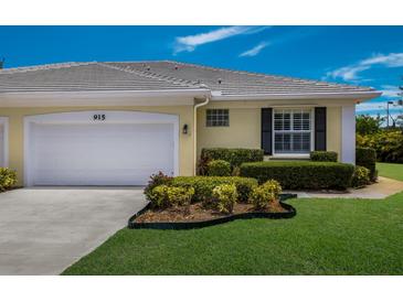 Charming single-story home featuring a well-manicured lawn, white garage door and a neatly landscaped garden at 915 Sw Barclay Ct, Venice, FL 34293