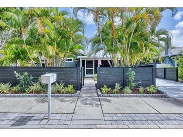 Charming home with a dark grey privacy fence surrounded by lush landscaping and beautiful palm trees at 1919 Laurel St, Sarasota, FL 34236