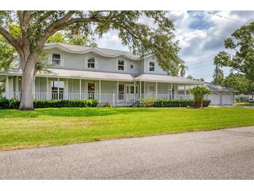 Inviting home showcasing a charming wrap-around porch and a well-maintained lawn with mature tree at 2002 8Th W St, Palmetto, FL 34221