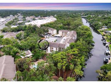 Scenic aerial view of the condo, pool and canal, surrounded by lush greenery and serene waters at 2740 Orchid Oaks Dr # 304, Sarasota, FL 34239