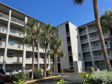 Low angle shot of the condo building with balconies and palm trees under a bright blue sky at 3272 Lake Bayshore Dr # 515, Bradenton, FL 34205