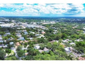 Expansive aerial view showcasing the neighborhood's lush greenery, blue skies, and vibrant cityscape at 3837 Camino Real, Sarasota, FL 34239
