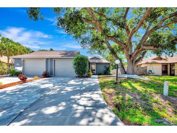 Charming single-story home featuring a spacious two-car garage and a lush, mature tree in the front yard at 5192 Cedar Hammock Ln, Sarasota, FL 34232