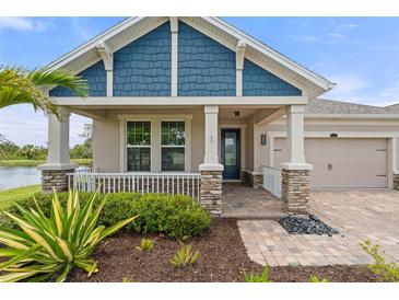 Inviting home entrance with stone accents, blue shingle siding, and charming front porch landscaping at 5240 Bentgrass Way, Bradenton, FL 34211