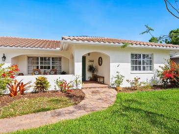 Charming home with lush landscaping and a welcoming brick pathway to the front door at 7460 Dickens Dr, Sarasota, FL 34231