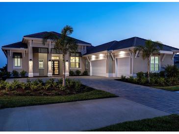 Elegant home exterior boasts a three-car garage, lush landscaping, and a paved driveway at 1198 Blue Shell Loop, Sarasota, FL 34240
