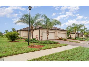 Charming home featuring a barrel tile roof, lush landscaping, and a paver driveway leading to a two-car garage at 12515 Garibaldi Ln, Venice, FL 34293