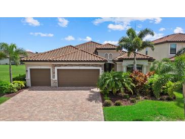 Charming home with a tile roof, a three-car garage, a brick paver driveway, and lush landscaping at 14216 Florida Rosemary Dr, Bradenton, FL 34211