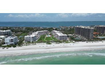 Stunning aerial view of beachfront condos with pristine beach, blue ocean, and well-manicured landscaping at 1445 Gulf Of Mexico Dr # 203, Longboat Key, FL 34228
