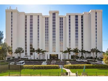 Modern condo building with a manicured lawn, palm trees, and parking spaces at 2425 Gulf Of Mexico Dr # 14B, Longboat Key, FL 34228