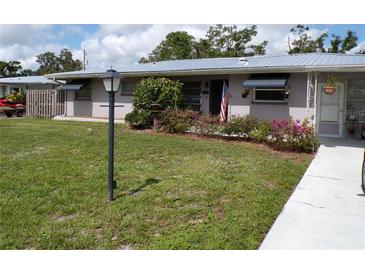 Charming single-story home with a metal roof, a well-manicured lawn, and colorful flowering bushes enhancing its curb appeal at 2787 Jay Pl, Sarasota, FL 34235