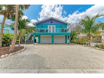 Charming coastal home with vibrant turquoise and purple exterior, balcony, and a two-car garage at 315 Magnolia Ave, Anna Maria, FL 34216