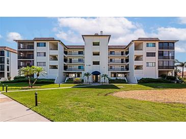 Beautiful condo with a well-manicured lawn, palm trees, and a blue awning covered entryway at 3630 Gulf Of Mexico Dr # 202, Longboat Key, FL 34228
