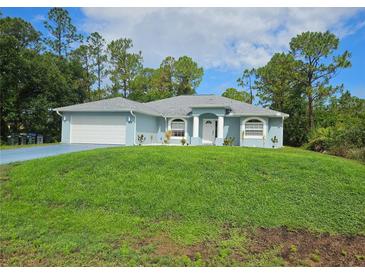 Charming single-story home featuring a well-manicured lawn, lovely blue exterior, and an attached two-car garage at 5849 Wagon Wheel Dr, North Port, FL 34291