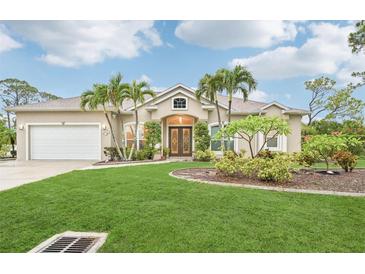 Charming home featuring a well-manicured lawn, palm trees, and a two-car garage at 5988 Viola Rd, Venice, FL 34293