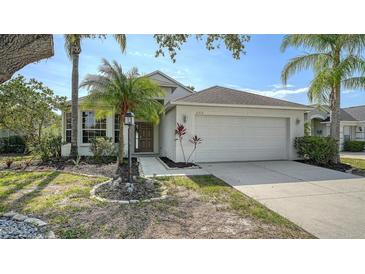 Charming single-story home featuring a well-manicured lawn, palm trees, and a two-car garage at 6213 Willet Ct, Lakewood Ranch, FL 34202