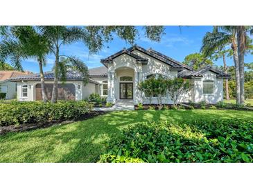Stunning white home featuring lush landscaping, an arched entrance, tile roof, and beautiful palm trees at 6641 Saint James Xing, University Park, FL 34201