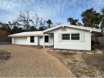 A charming single-story home with white exterior, gravel driveway, and minimal landscaping set against a cloudy sky at 782 Birdsong Ln, Sarasota, FL 34242