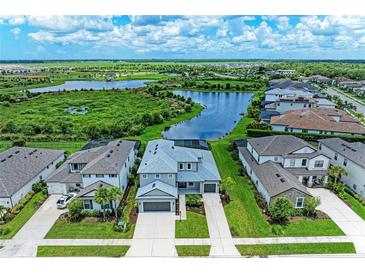 Breathtaking aerial view of a two-story home with a lake view and well-manicured landscaping at 8264 Summer Night Rd, Sarasota, FL 34241
