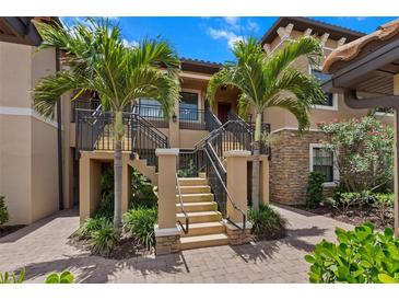 Inviting condo exterior showcasing landscaped entry with palm trees and a charming stairway leading to the upper level entrance at 13810 Messina Loop # 202, Bradenton, FL 34211