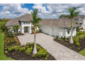 Beautiful home exterior with a large driveway, three-car garage, and professional landscaping with palm trees at 8218 Genoa Blvd, Lakewood Ranch, FL 34202